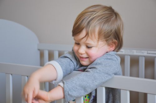 A smiling toddler inside a crib